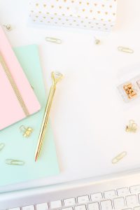 Golden pen notepads and keyboard on white background